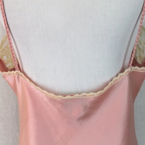 May include: A pink satin slip with delicate lace trim around the neckline and straps.