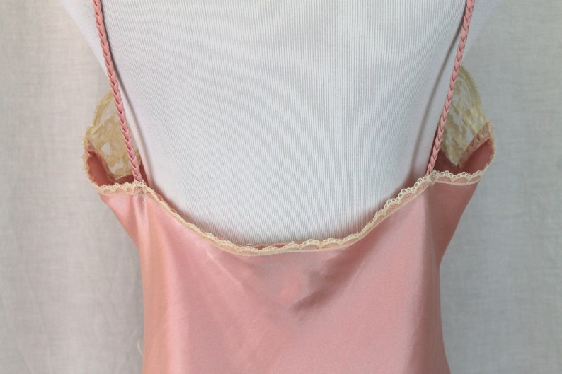 May include: A pink satin slip with delicate lace trim around the neckline and straps.