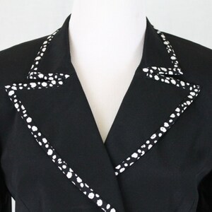 May include: A black blazer with a white polka dot trim around the collar.