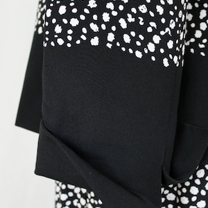 May include: Black and white polka dot fabric with a black fold-over cuff. The fabric has a subtle texture.
