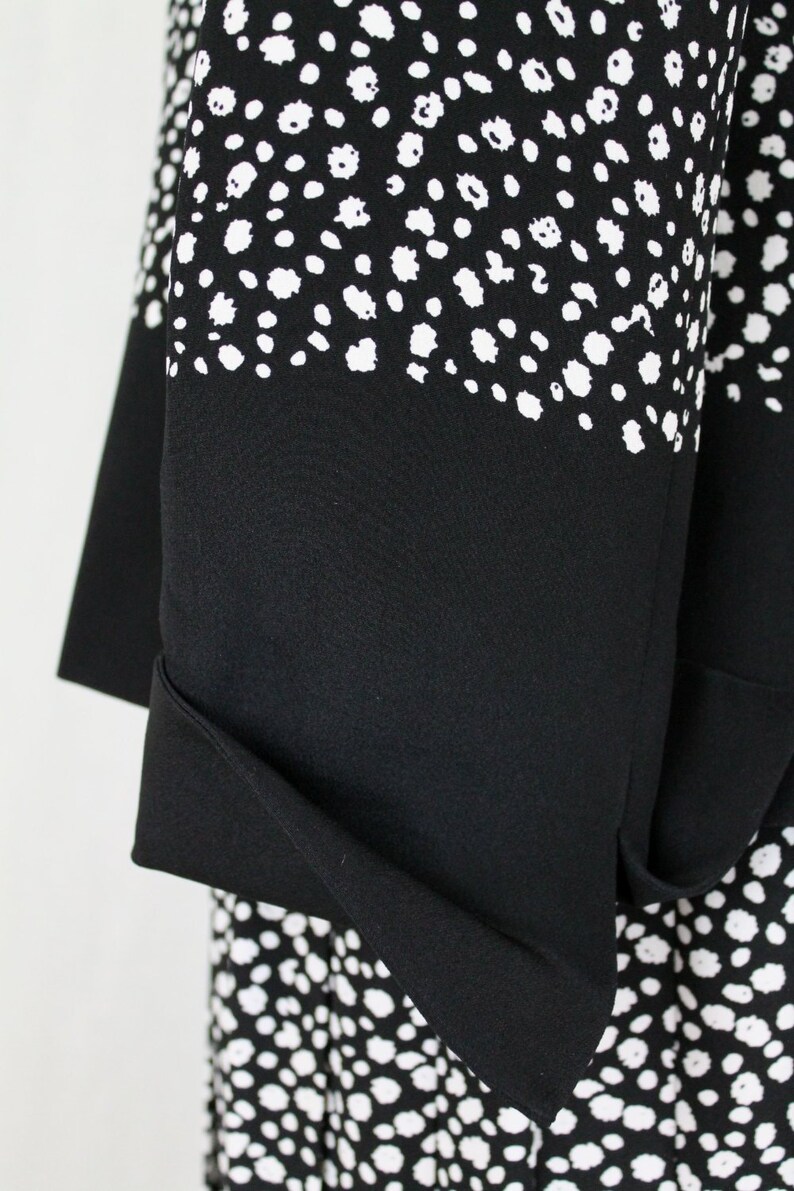 May include: Black and white polka dot fabric with a black fold-over cuff. The fabric has a subtle texture.