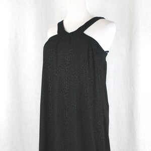 May include: A black sleeveless dress with a halter neckline and a leopard print pattern. The dress has a loose, flowing fit and a gathered waist.