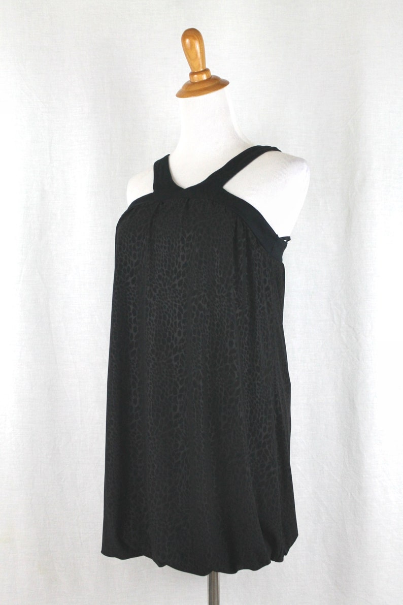 May include: A black sleeveless dress with a halter neckline and a leopard print pattern. The dress has a loose, flowing fit and a gathered waist.