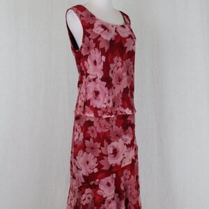 May include: A sleeveless red and pink floral print dress with a ruffled hemline. The dress is on a white background.