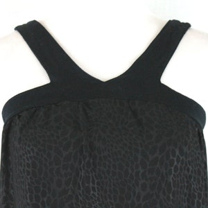 May include: Black sleeveless dress with a leopard print pattern and a black V-neck top.