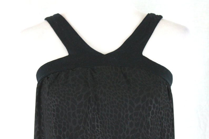 May include: Black sleeveless dress with a leopard print pattern and a black V-neck top.