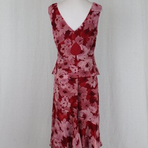 May include: A sleeveless, knee-length dress with a floral print in shades of pink and red. The dress has a fitted bodice and a flowing skirt.