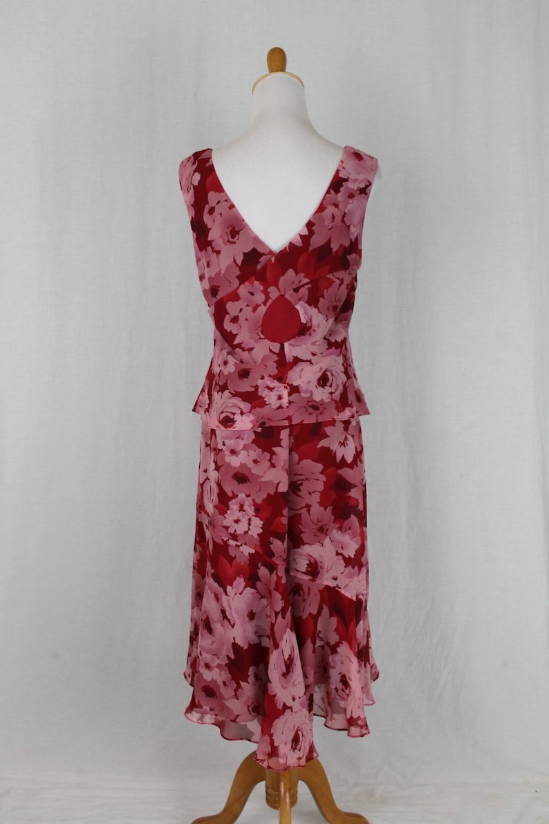 May include: A sleeveless, knee-length dress with a floral print in shades of pink and red. The dress has a fitted bodice and a flowing skirt.