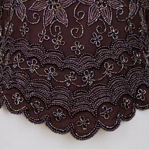 May include: A brown beaded top with a scalloped hem and a floral design. The beads are iridescent and create a shimmering effect.