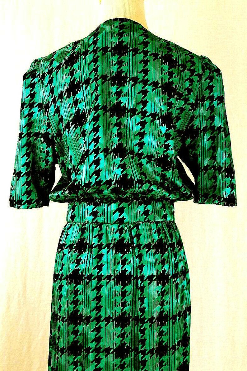 May include: A green and black dress with a houndstooth pattern. The dress has a short sleeve and a fitted waist.