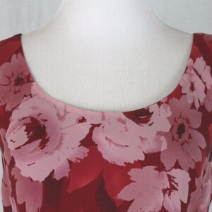 May include: A sleeveless red dress with a pink floral print. The dress has a scoop neckline and a fitted bodice.