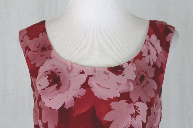 May include: A sleeveless red dress with a pink floral print. The dress has a scoop neckline and a fitted bodice.