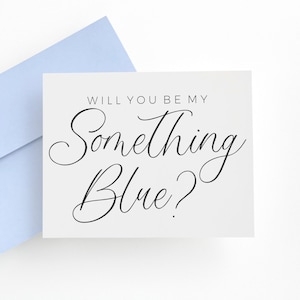 May include: A white rectangular greeting card with black text that reads "WILL YOU BE MY Something Blue?" in a combination of sans-serif and cursive script fonts, accompanied by a light blue envelope positioned behind the card.