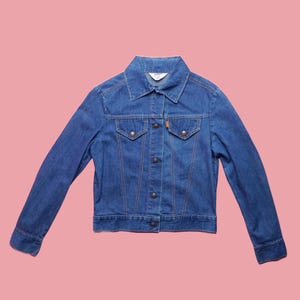 May include: A blue denim jacket with a button closure and two front pockets.