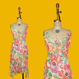 May include: A white dress with a floral print in shades of pink, orange, and green. The dress has a ruffled neckline and a flowing skirt.