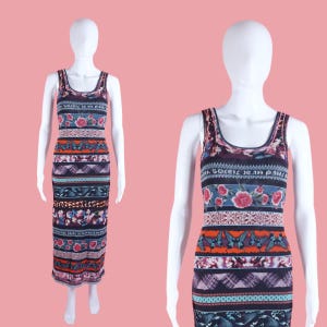 May include: A sleeveless midi dress featuring a multi-colored horizontal print with floral motifs, butterflies, and geometric patterns. The fabric displays the text "SOLEIL JEAN PAUL" repeatedly across the dark blue background on a white mannequin.