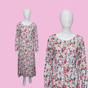 May include: A long-sleeved floral dress with a white background and pink, blue, and green flowers. The dress has a button-up front and a slightly flared skirt.