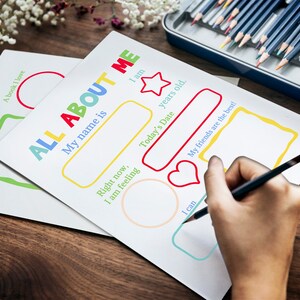 A hand is seen filling out the pages of this printable all about me booklet.
