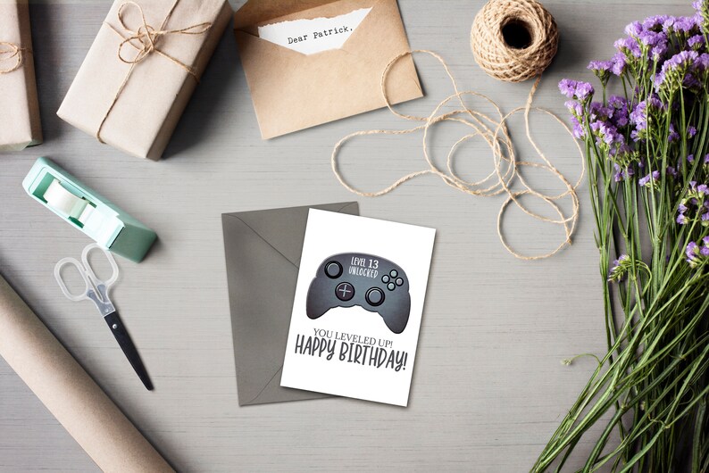 May include: A white card with a gray video game controller graphic and the text "Level 13 Unlocked" and "You Leveled Up! Happy Birthday!"