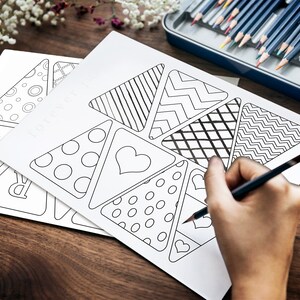 A hand is seen holding a pencil crayon about to start coloring in the pennant flags.