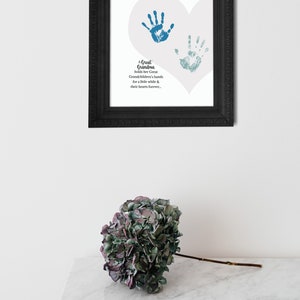 May include: A framed print with a white heart shape and two blue handprints inside. The text reads "A Great Grandma holds her Great Grandchildren's hands for a little while & their hearts forever."
