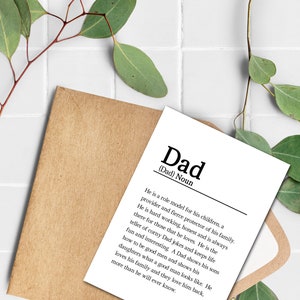 May include: A white card with black text defining the word "Dad" as a role model, provider, and protector of his family. The card is on a brown envelope with green leaves on a white tiled background.
