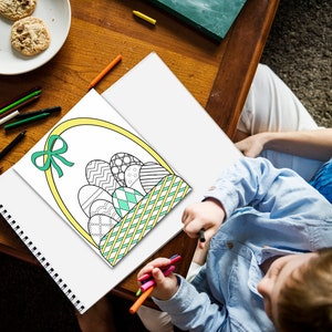 May include: A child colors in a black and white drawing of a basket filled with Easter eggs. The basket is yellow with a green and white checkered pattern. The eggs are decorated with different patterns.