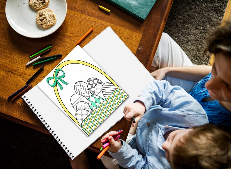 May include: A child colors in a black and white drawing of a basket filled with Easter eggs. The basket is yellow with a green and white checkered pattern. The eggs are decorated with different patterns.