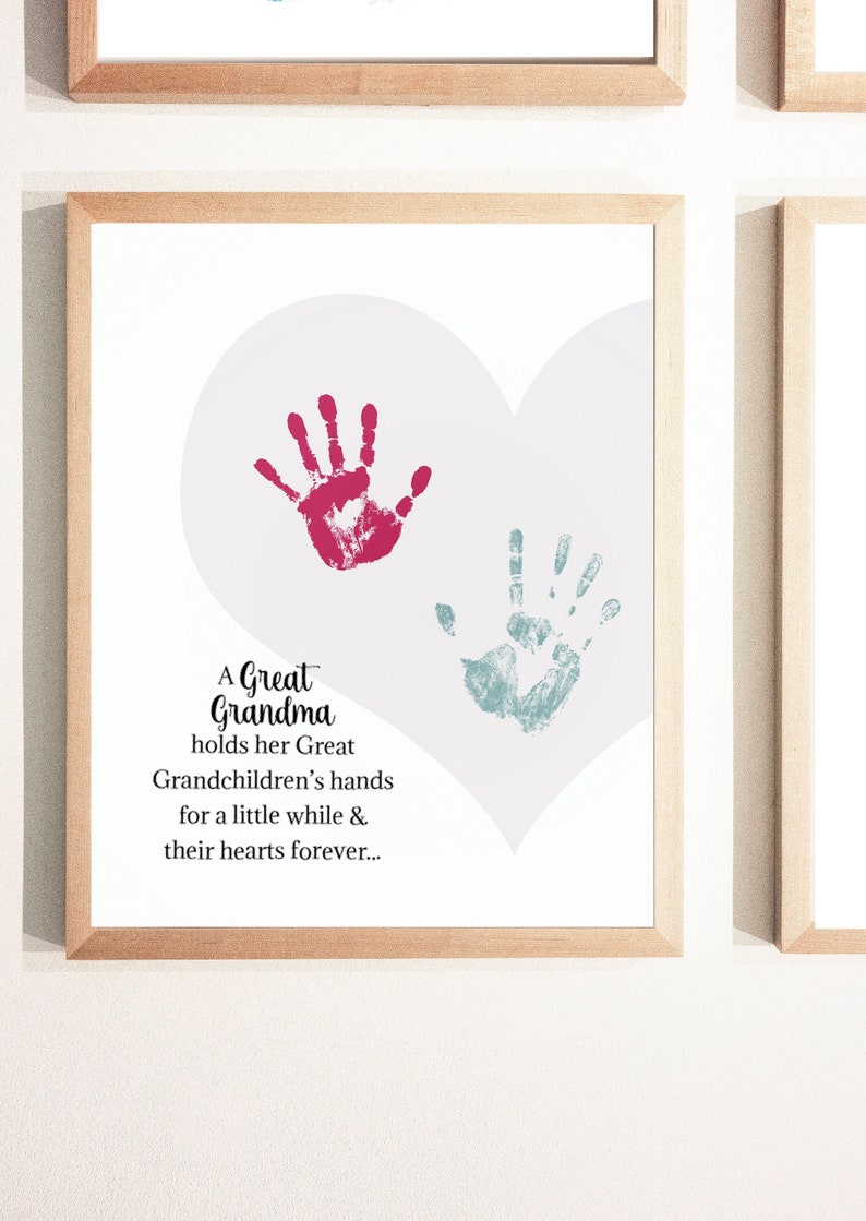 May include: A framed print with a pink heart shape and two handprints inside. The handprints are in red and blue. The text reads: "A Great Grandma holds her Great Grandchildren's hands for a little while & their hearts forever..."