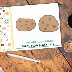 May include: A white card with two cartoon cookies and the text "I love when my Mom bakes cookies with me!". The card has a decorative border with colorful circles and a pen.