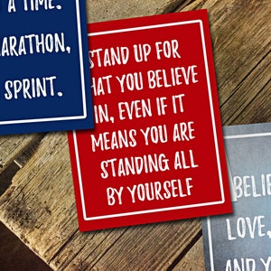 May include: Three inspirational quotes printed on colorful cards. The first card is blue with white text that reads "It's a marathon, not a sprint." The second card is red with white text that reads "Stand up for what you believe in, even if it means you are standing all by yourself." The third card is blue with white text that reads "Believe in love, magic and yourself."