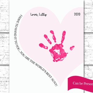 K&ouml;nnte beinhalten: Eine rosa herzf&ouml;rmige Karte mit einem rosa Handabdruck in der Mitte. Der Text "Love, Lilly" befindet sich oben auf der Karte. Der Text "I HAVE TO HAND IT TO YOU... YOU ARE THE WORLD'S BEST AUNT!" ist in einem Kreis um den Handabdruck geschrieben. Das Jahr "2020" befindet sich oben rechts auf der Karte. Der Text "Can be Personalized" befindet sich unten auf der Karte.