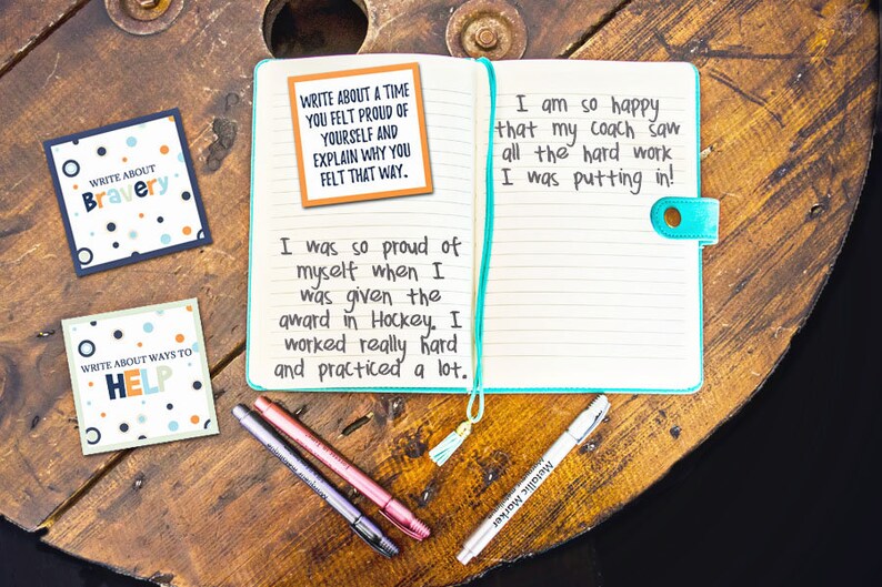 May include: A notebook with a turquoise cover and lined pages. The notebook is open and has a note card on the left page that says "Write about a time you felt proud of yourself and explain why you felt that way." The right page has handwritten text that says "I am so happy that my coach saw all the hard work I was putting in!" and "I was so proud of myself when I was given the award in Hockey. I worked really hard and practiced a lot."