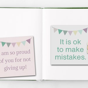 May include: Two motivational notes with a pastel color scheme and a string of flags on top. The left note says "I am so proud of you for not giving up!" and the right note says "It is ok to make mistakes."