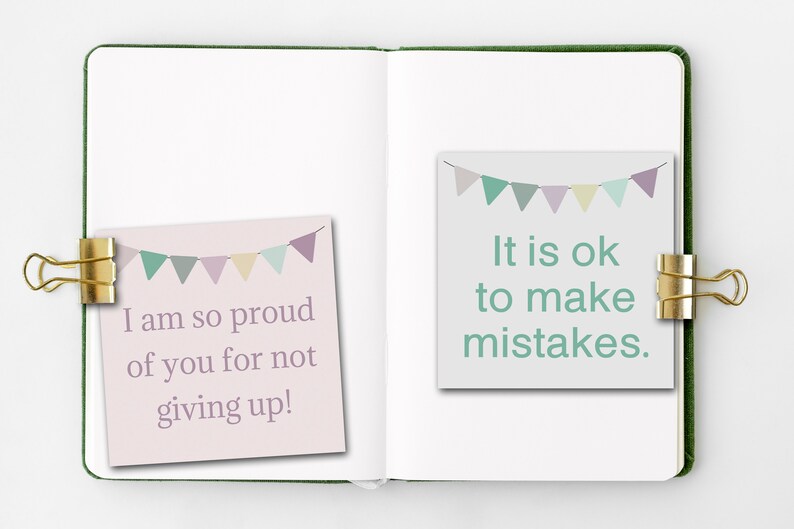 May include: Two motivational notes with a pastel color scheme and a string of flags on top. The left note says "I am so proud of you for not giving up!" and the right note says "It is ok to make mistakes."