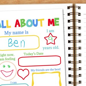 A notebook sits with the title page of the printable all about me booklet. A child has started filling in his book.