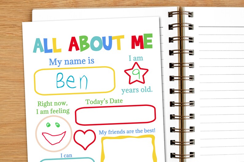 A notebook sits with the title page of the printable all about me booklet. A child has started filling in his book.