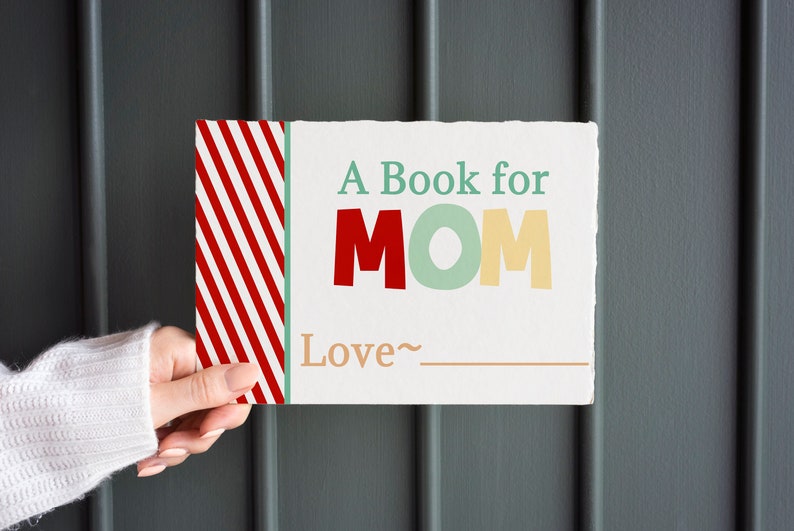 May include: A rectangular book with the text "A Book for MOM" in red, green, and yellow letters. The book has a red and white striped design on the left side and the word "Love" with a line for a signature.