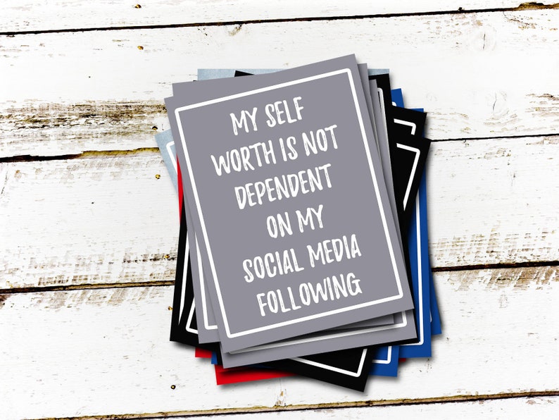 May include: A stack of gray, black, blue, and red cards with white text that reads "My self worth is not dependent on my social media following."