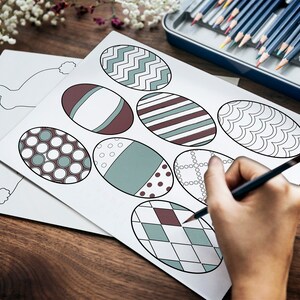 May include: A sheet of paper with eight outlined Easter eggs, each with a different pattern. A person is coloring one of the eggs with a pencil.