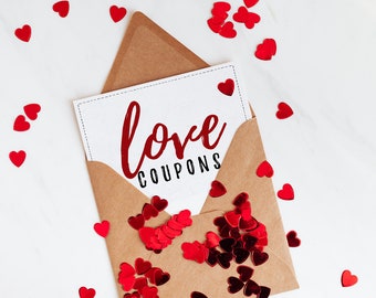 May include: A white card with the text "love coupons" in red lettering, inside a brown envelope. Red heart confetti is scattered around the envelope.