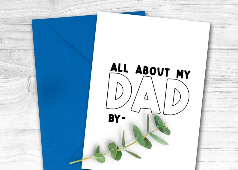 May include: A white card with black text that reads "All About My Dad By-." The card is sitting on a wooden surface with a sprig of greenery.
