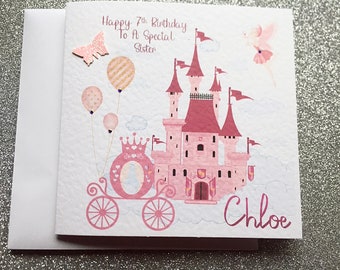 May include: A pink birthday card with a fairy tale theme. The card features a pink castle, a carriage, balloons, and a fairy. Text on the card reads "Happy 7th Birthday To A Special Sister" and the name "Chloe". A pink glitter butterfly is attached.