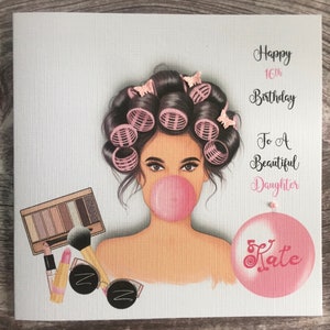 May include: A pink and white birthday card featuring a drawing of a woman with pink hair rollers and a pink bubble. The card reads "Happy 16th Birthday To A Beautiful Daughter Kate".
