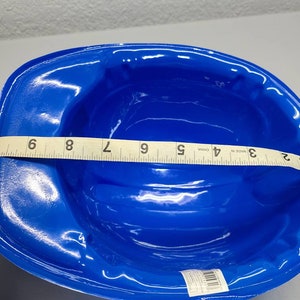 May include: A blue plastic hard hat for construction workers. The hat is 7 inches wide. Made in China.