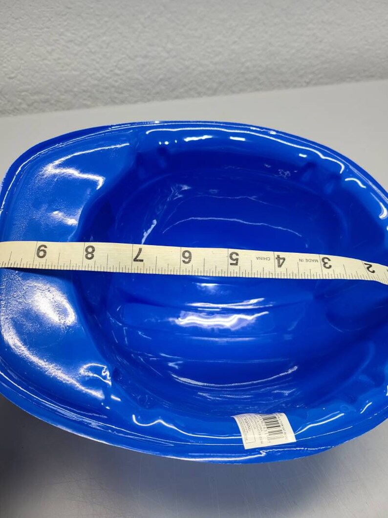 May include: A blue plastic hard hat for construction workers. The hat is 7 inches wide. Made in China.