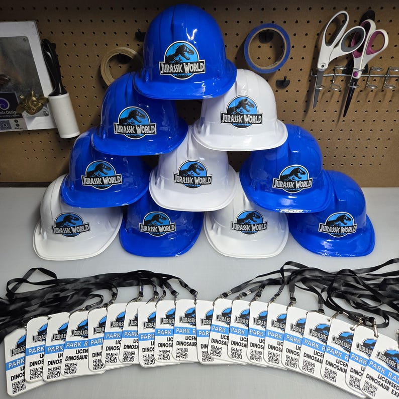 May include: A set of 12 blue and white hard hats with the Jurassic World logo. Each hat comes with a black lanyard and a white card that says "Park Ranger Licensed Dinosaur Expert".