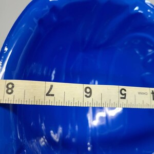May include: A bright blue ceramic bowl with a wavy, textured surface. The bowl is 9 inches in diameter.