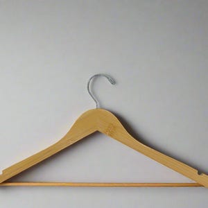 May include: A wooden clothes hanger with a metal hook. The hanger is light brown and has a smooth finish.