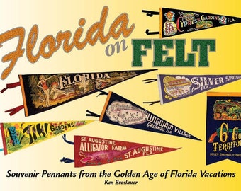 May include: A collection of vintage felt pennants featuring Florida attractions, including Cypress Gardens, Silver Springs, and St. Augustine Alligator Farm. The pennants are displayed against a yellow background with the text "Florida on Felt" in large, glittery letters. The text "Souvenir Pennants from the Golden Age of Florida Vacations" is printed below the pennants.
